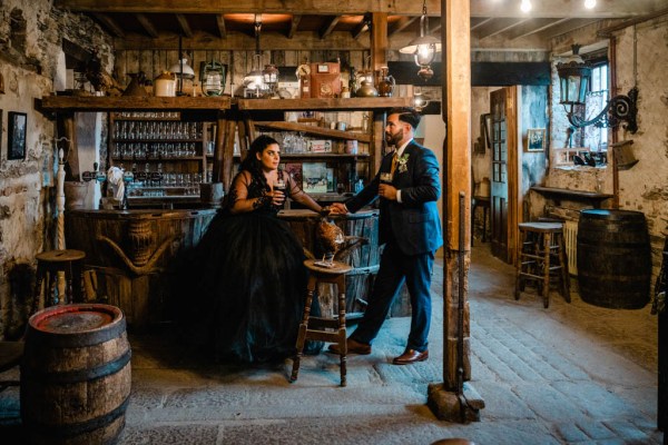 Bride and groom drink pints of Guinness in bar setting holding hands