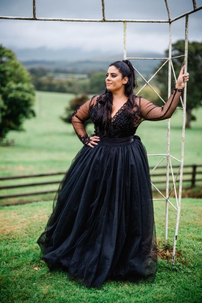 Bride poses in garden farm fence in background