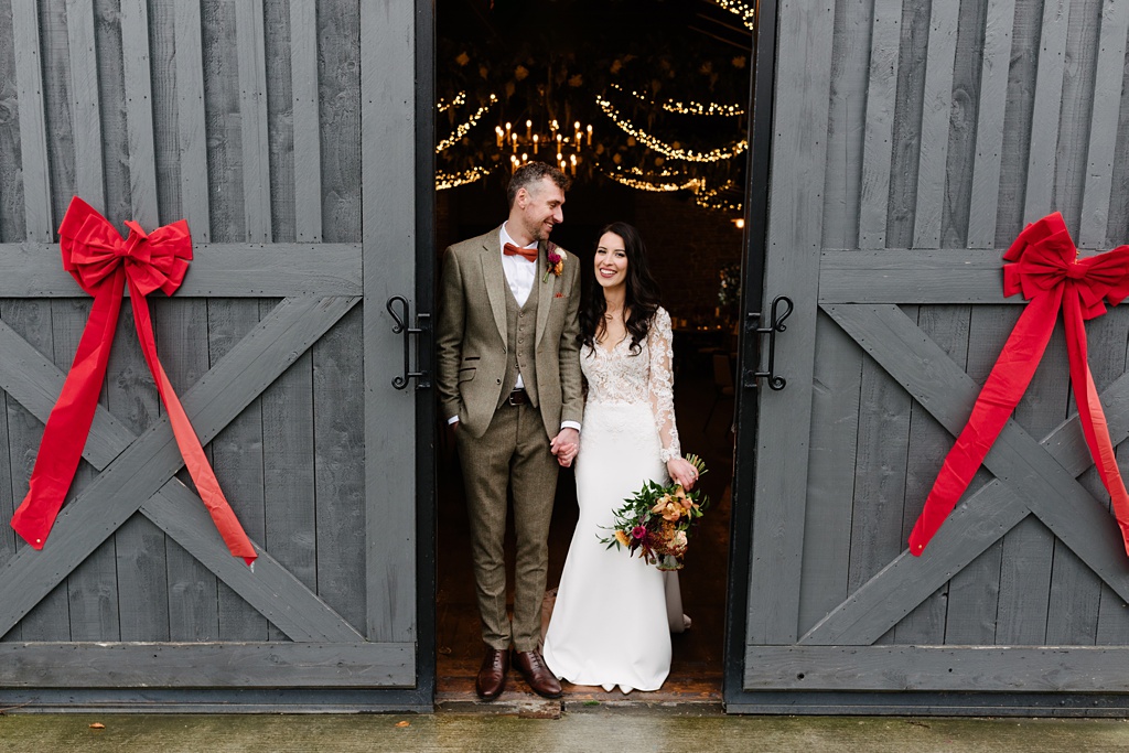 Red ribbons bows either side of bride and groom at entry to dining room interior