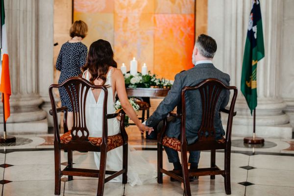 Bride and groom seated holding hands in front of officiant