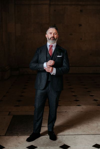 Groom stands on his own checkered floor tiles looking at watch