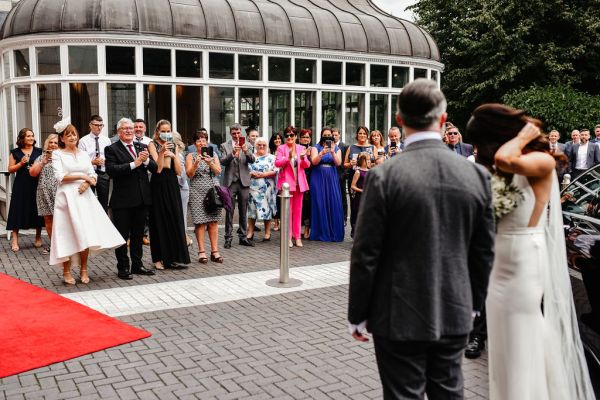 Exterior guests setting clapping at couple