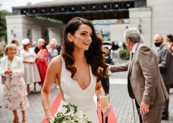 Bride wavy hair detail holding prosecco and flowers