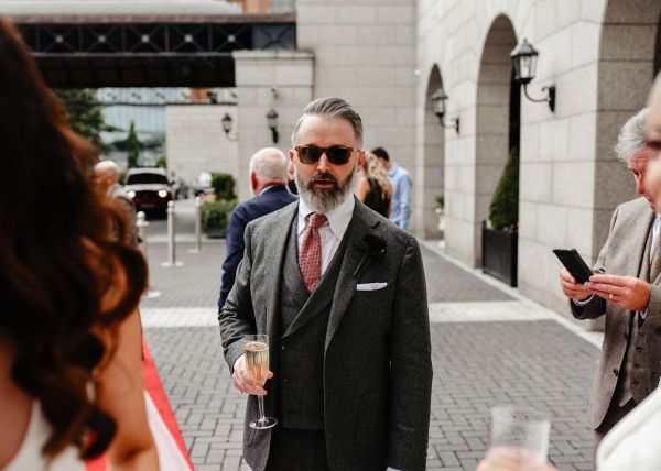 Groom drinks champagne outside wedding venue