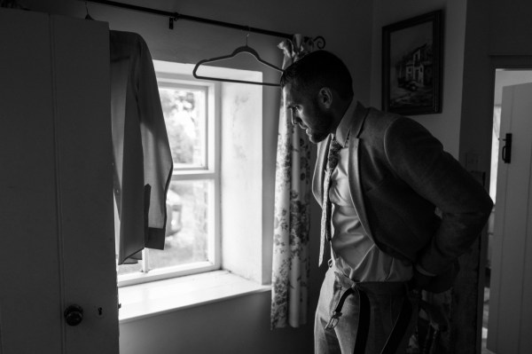 Black and white image of groom looking out of window