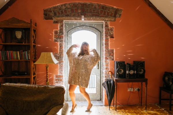 Woman stands at door gold outfit and heels