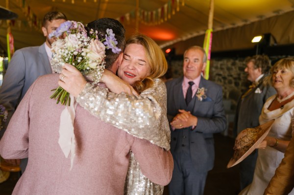 Guests mother hugs the groom holding bouquet