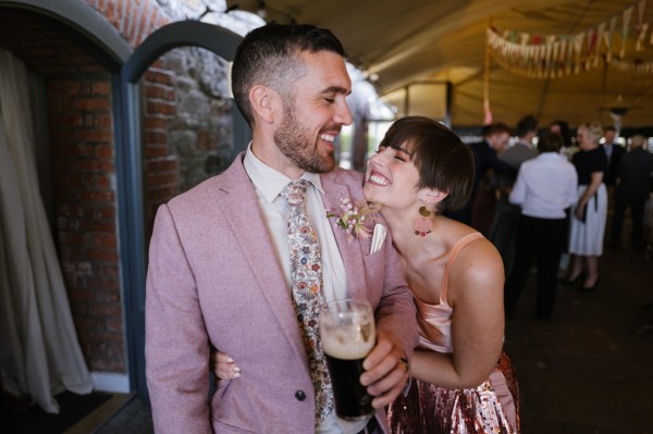 Friend and groom holding Guinness smiles