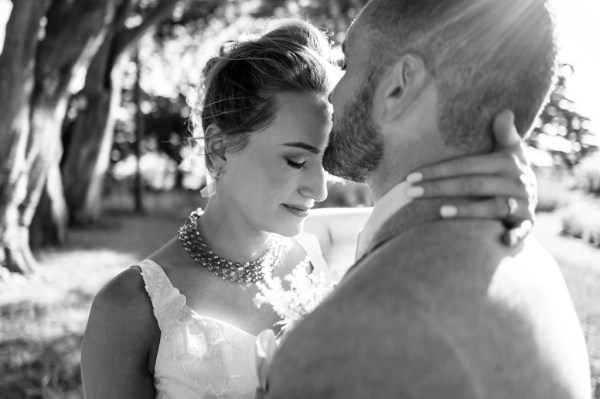 Bride and groom black and white hand around neck in park forest setting