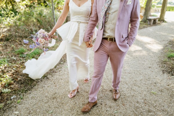 Bride and groom walk along pathway in park