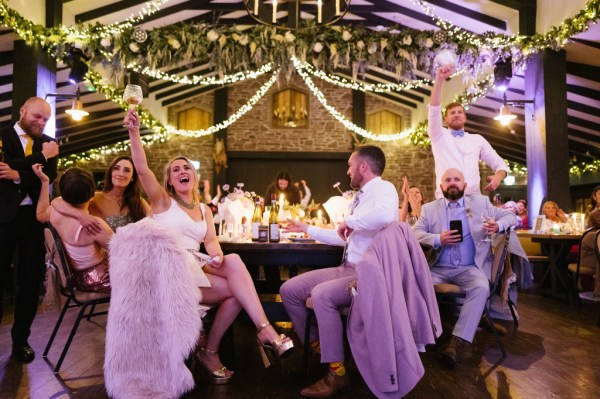 Bride and groom celebrating cheers with wine guests seated