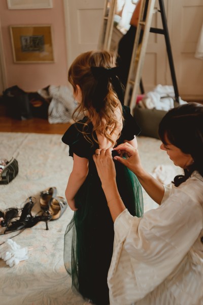 Woman fixing back of dress of little girl