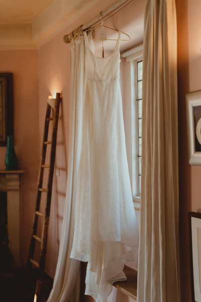 Bridal gown dress is hanging beside window