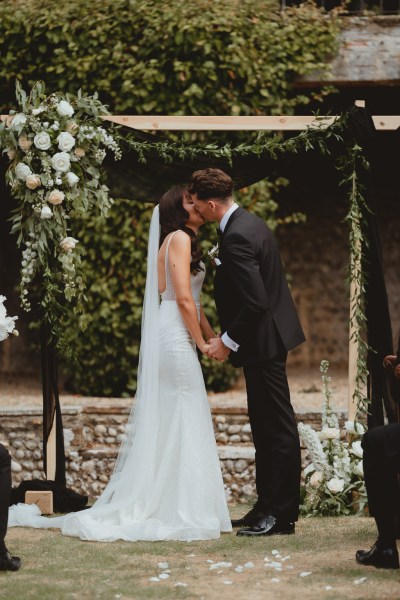 Bride and groom kiss at the alter during wedding ceremony