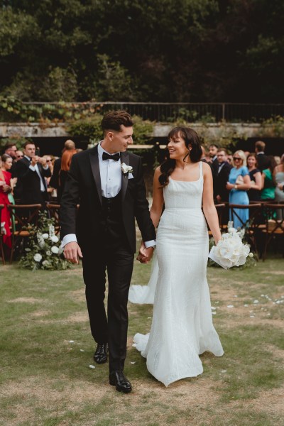 Bride and groom walk look at each other holding hands