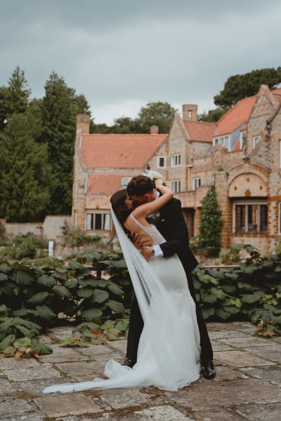 Bride and groom kiss kissing in front of wedding venue