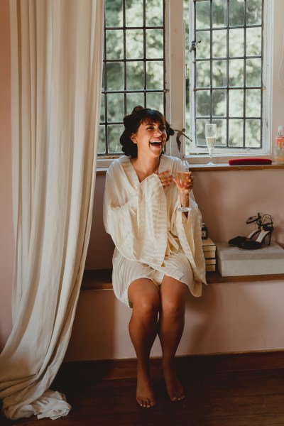 Bride laughs and smiles sitting at window