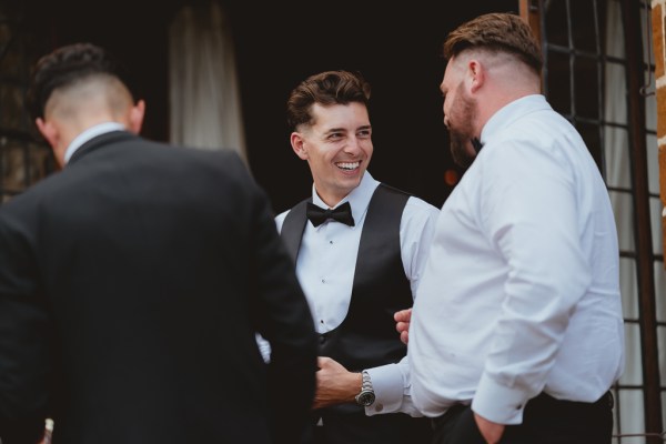 Groom smiles with groomsmen exterior shot