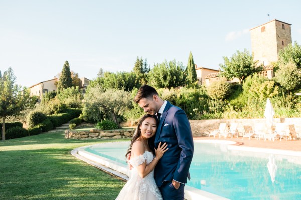 Trees landscape in background bride and groom in front of fountain pool