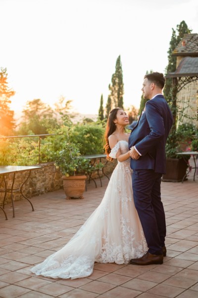 Bride and groom look at each other smiling sunset