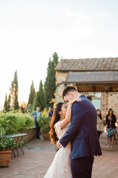 Bride and groom hug dance outside wedding venue