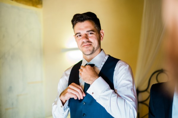 Groom fixes his tie getting ready