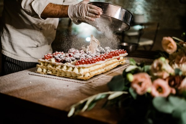 Baker icing being sprinkled over wedding cake