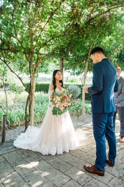 Bride looks at groom during wedding ceremony as he reads his vows