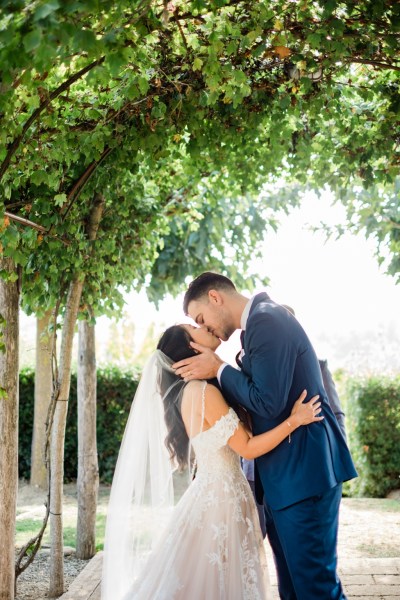 Groom kisses bride garden shot