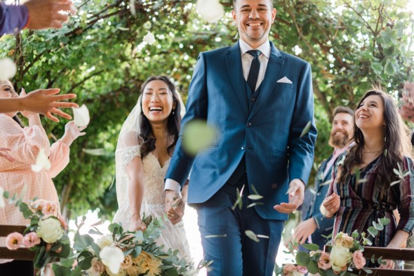 Bride and groom smiling surrounded by guests