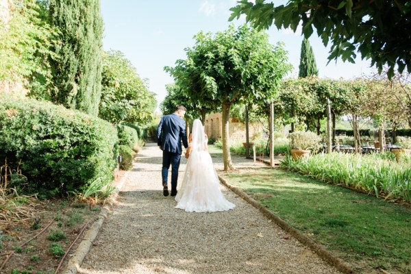 Bride and groom from behind walk in the garden