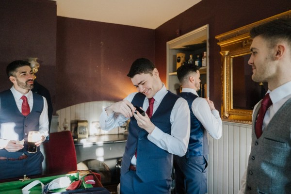 Groom and groomsmen in room getting ready shirt and tie