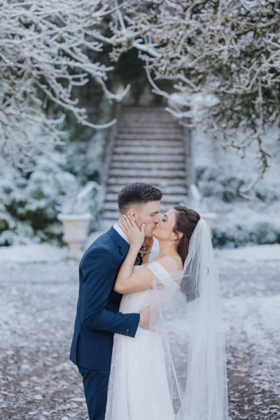 Stairs in background bride and groom kiss outside