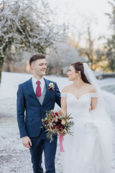 Bride and groom walking along pathway looking at each other