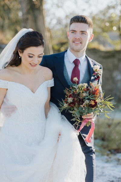 Bride and groom walk on snowy grass exterior shot