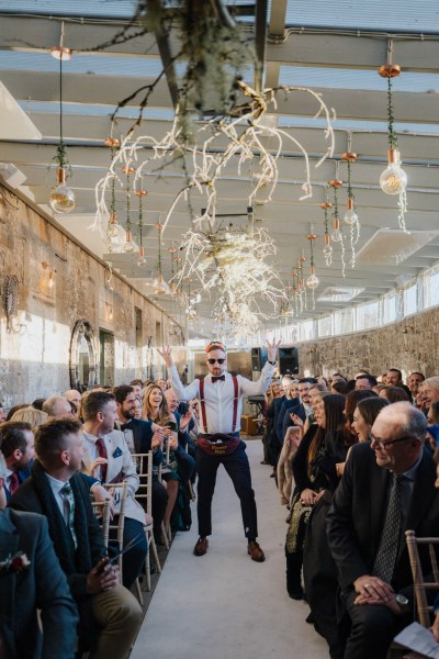 Groomsmen wearing sunglasses walks down the aisle guests laugh