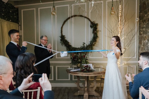 Bride and groom hold up the blue and white ribbon together