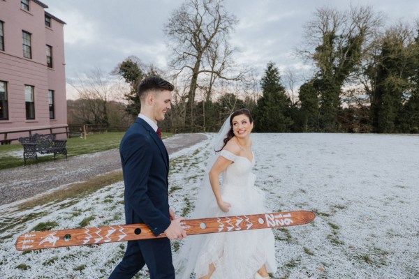 Bride and groom standing on the snowy grass have a shot we tied the knot