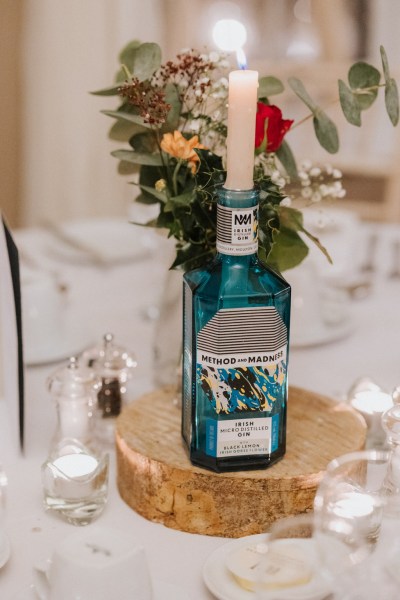 Bottle with candle inside it and flowers on table