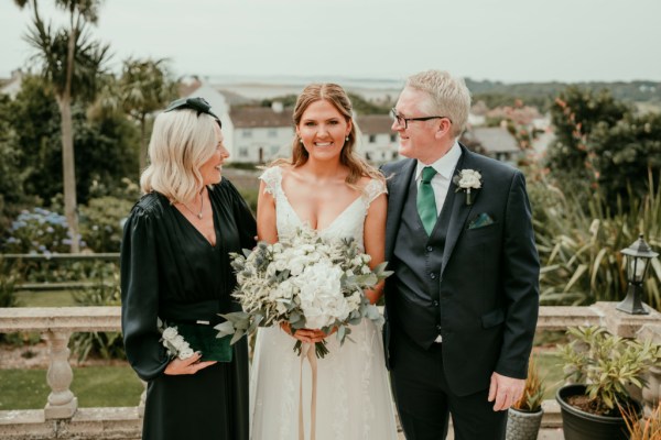 Mother and father look at bride holding bouquet