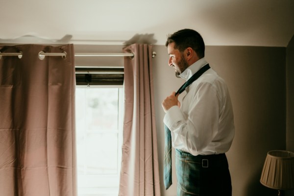 Groom putting on tie getting ready