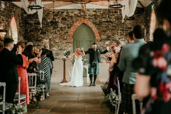 Bride and groom celebrate at alter in front of guests clapping