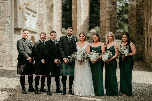 Group shot bride groom groomsmen bridesmaids pose for a picture