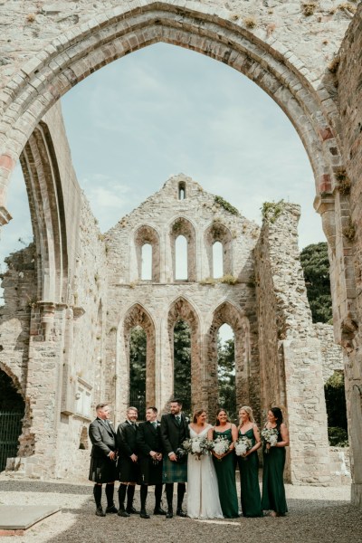 Group shot bride groom groomsmen bridesmaids pose for a picture castle exterior detail