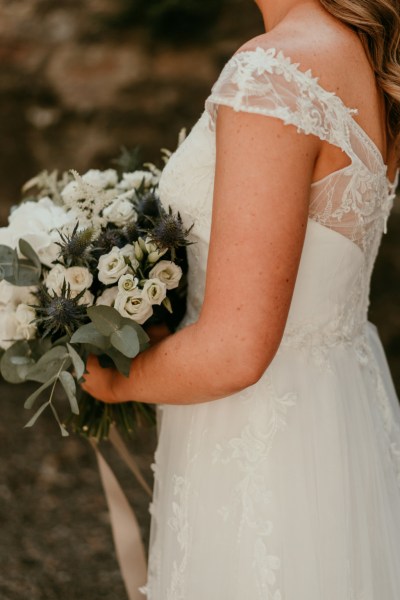 Close up of bridal lace gown and bouquet