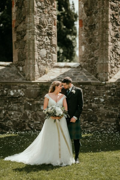 Couple touch foreheads outside of church setting on grass