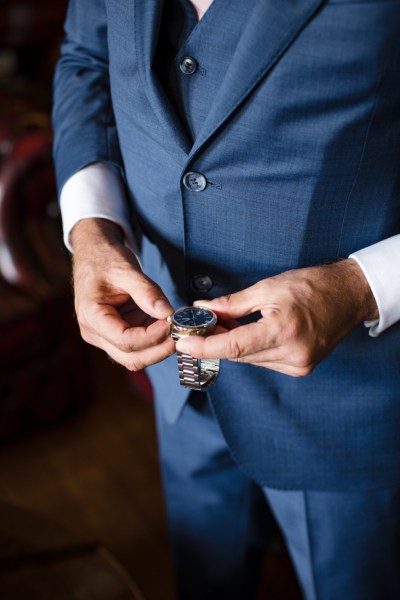 Groom with suit on getting ready looking at silver watch