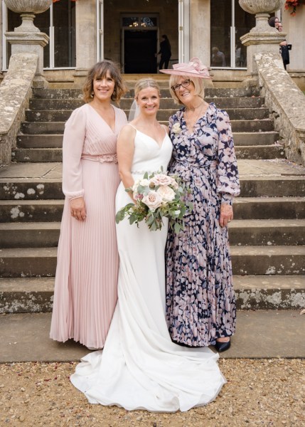 Mother bride and bridesmaid pose at bottom of steps