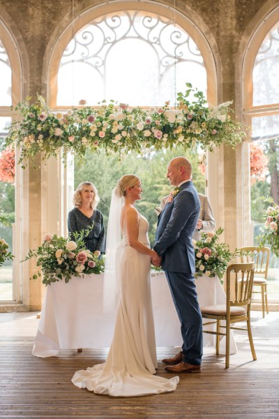 Bride groom celebrant at alter they hold hands