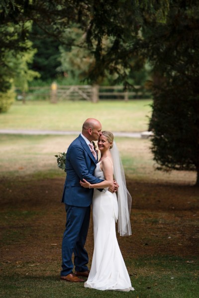 Bride and groom holding each other in forest park setting